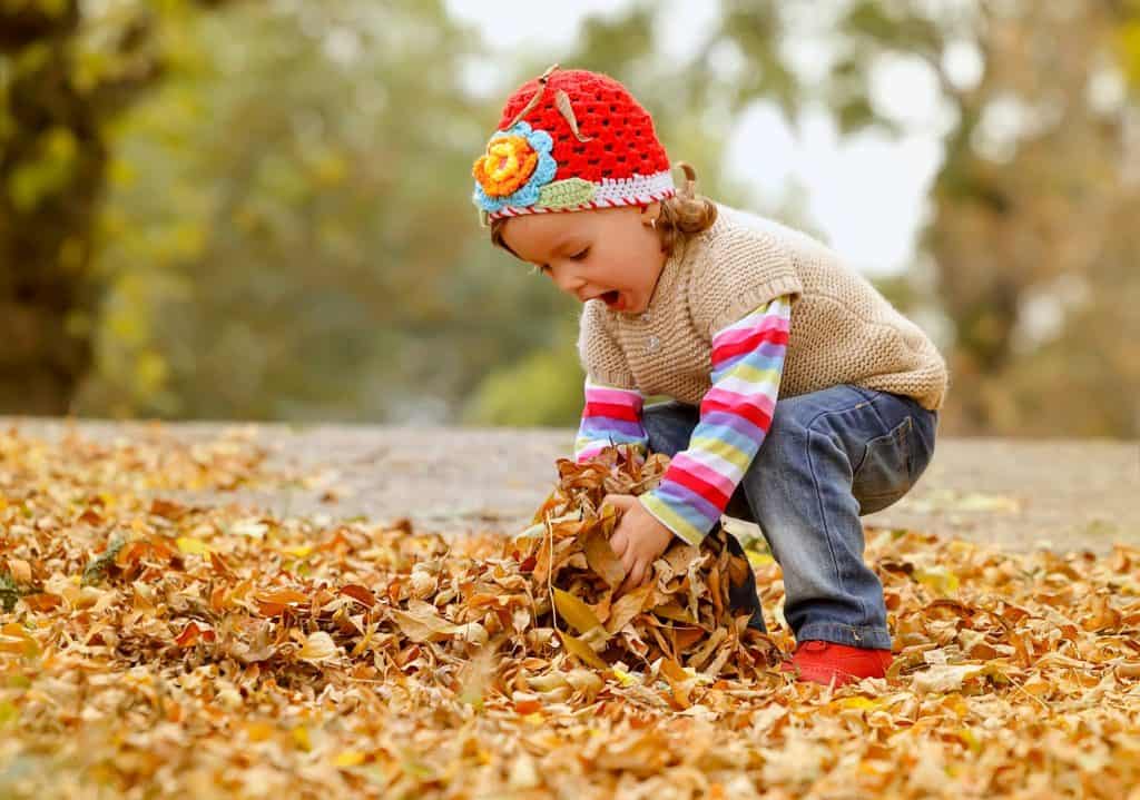 enfant joue dans les feuilles