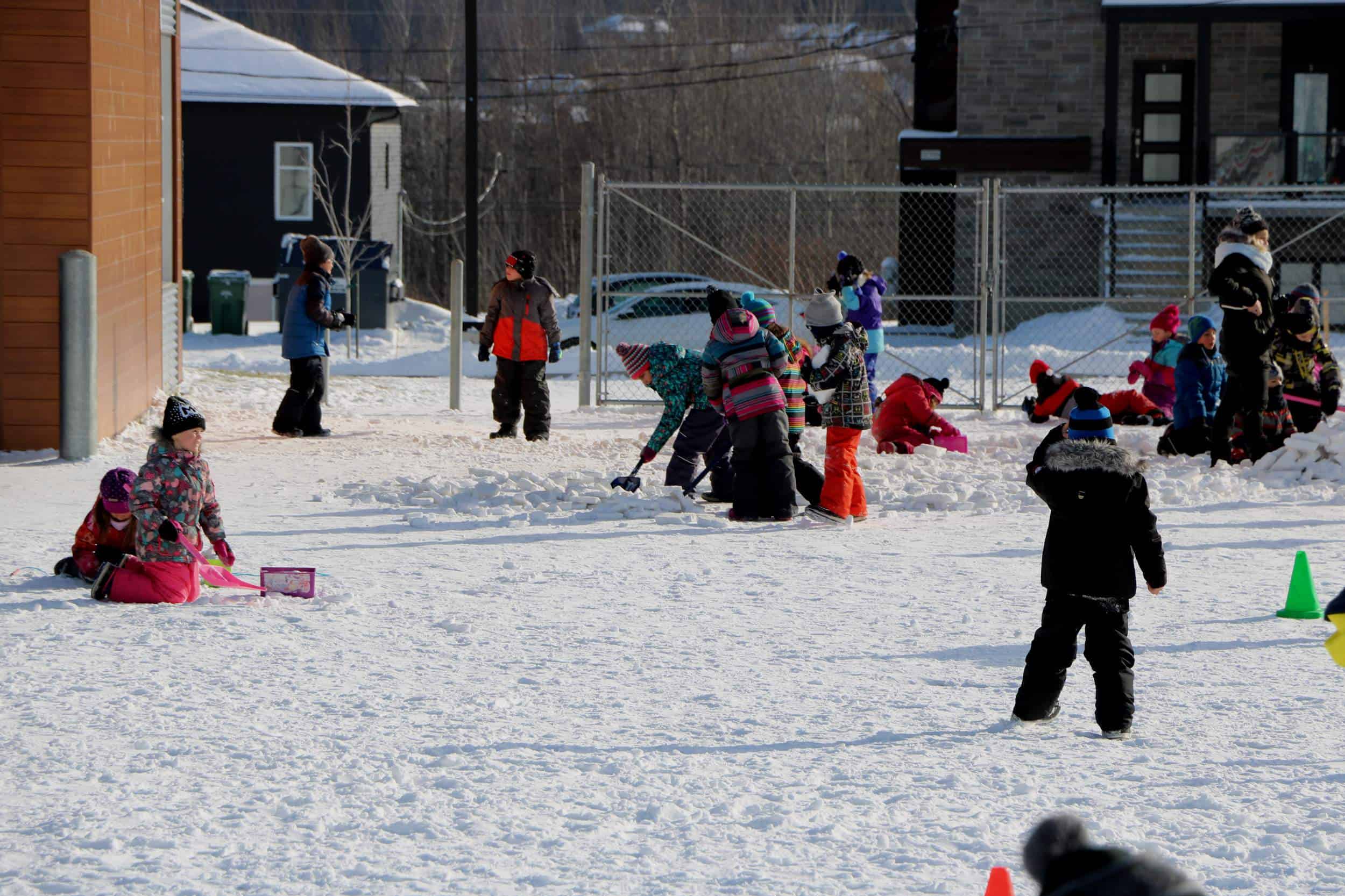 plusieurs enfants qui s'amusent en hiver dans une cour d'école