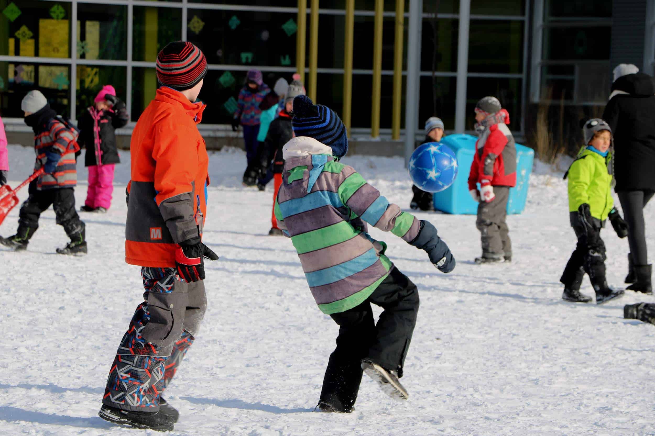 enfants qui jouent au soccer en hiver dans la cour d'école