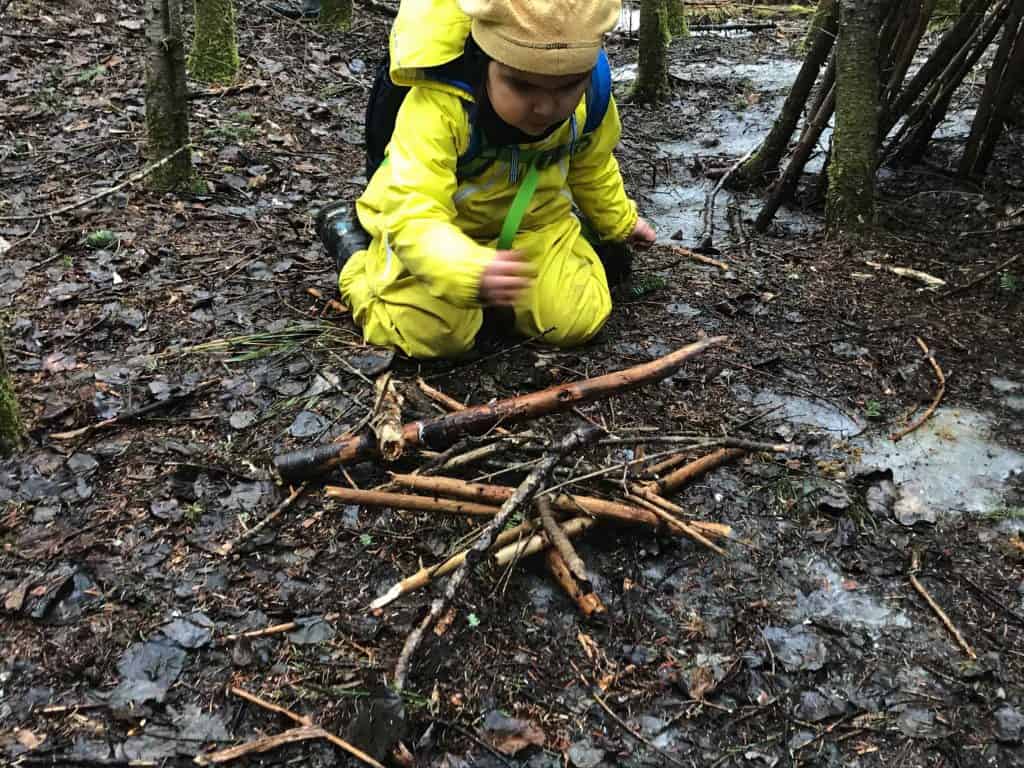 enfant fait un feu dans la foret